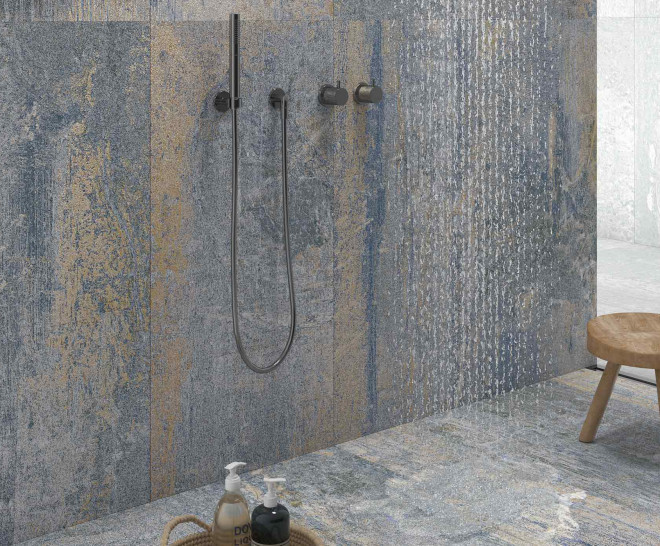 EROSION Baño moderno con azulejos azulados y grifería oscura. Mueble de madera al fondo.