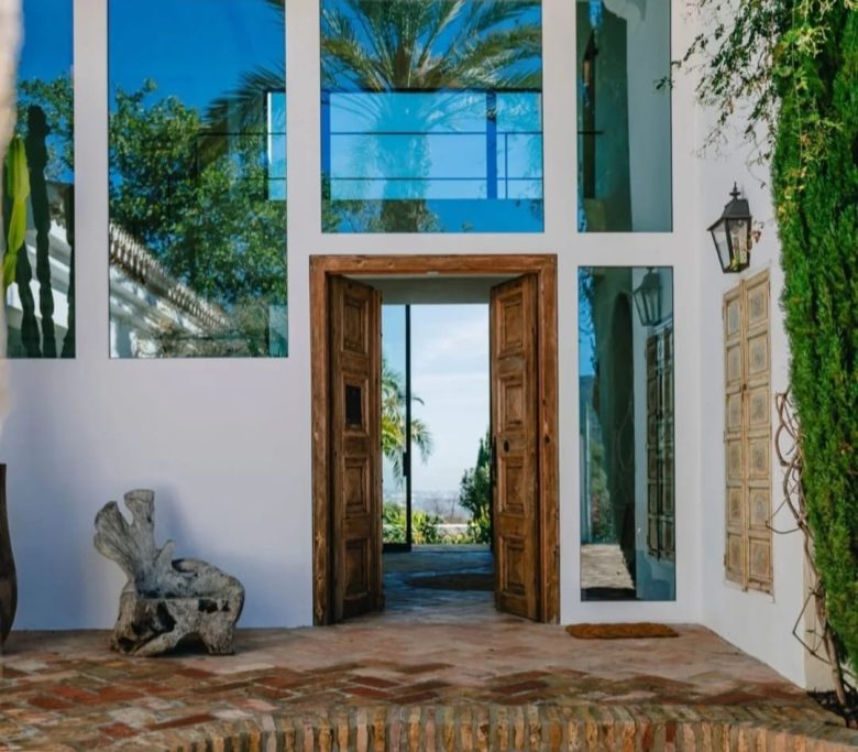 Resort exclusivo en Marbella Puerta de entrada con grandes ventanales y vista al exterior, rodeada de vegetación.