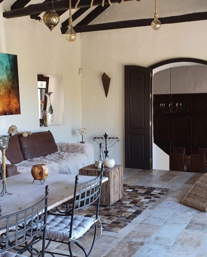 Cerámica para interiores Sala luminosa con sofá, mesa de café, decoraciones artísticas y puertas de madera.