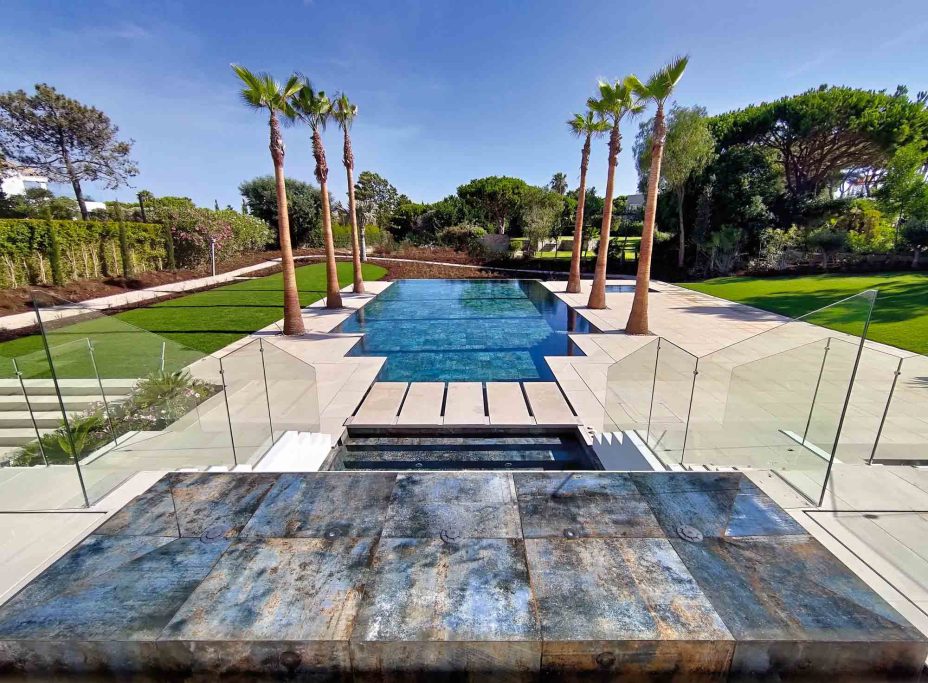 ALCHEMY Vista de un elegante patio con piscina y palmeras en un entorno natural.