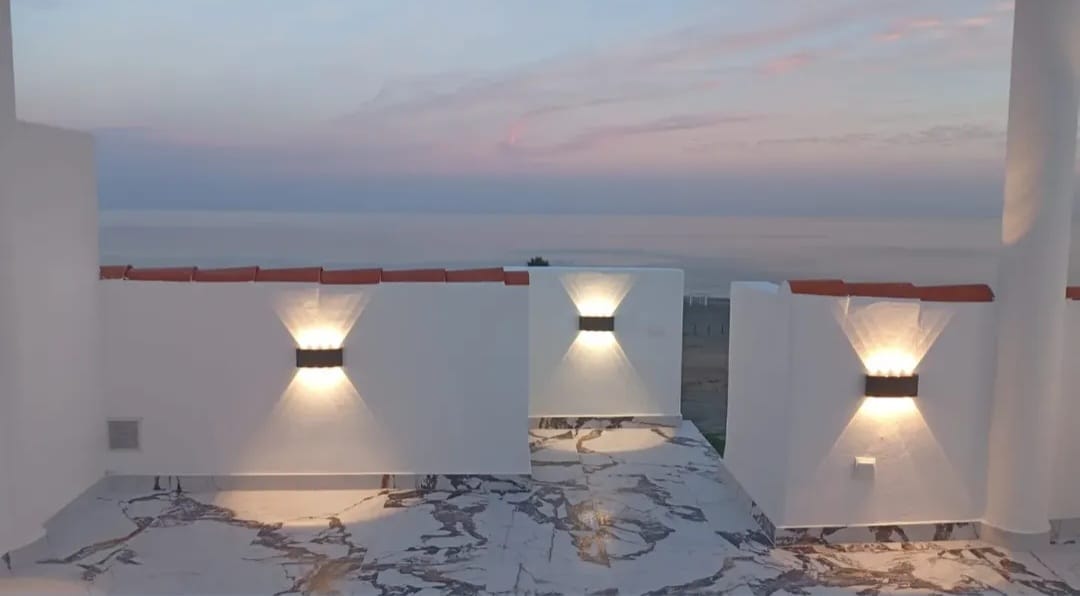 Porcelánicos para exteriores Terraza con luz suave, vista al mar y cielo en tonos pastel al atardecer.